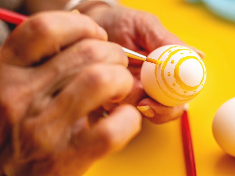 Woman painting an Easter egg with a brush