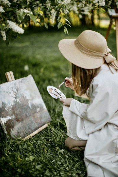 Frau mal im Freien ein Gemälde mit Ölfarben und Künstlerpinsel