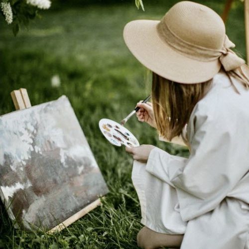 Frau mal im Freien ein Gemälde mit Ölfarben und Künstlerpinsel