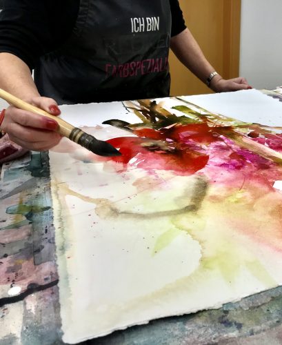 woman painting flowers with watercolor and an artist brush